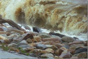 A wave crashing onto the rocks of the dike.